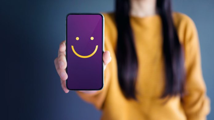 Woman holding phone displaying a smiley face